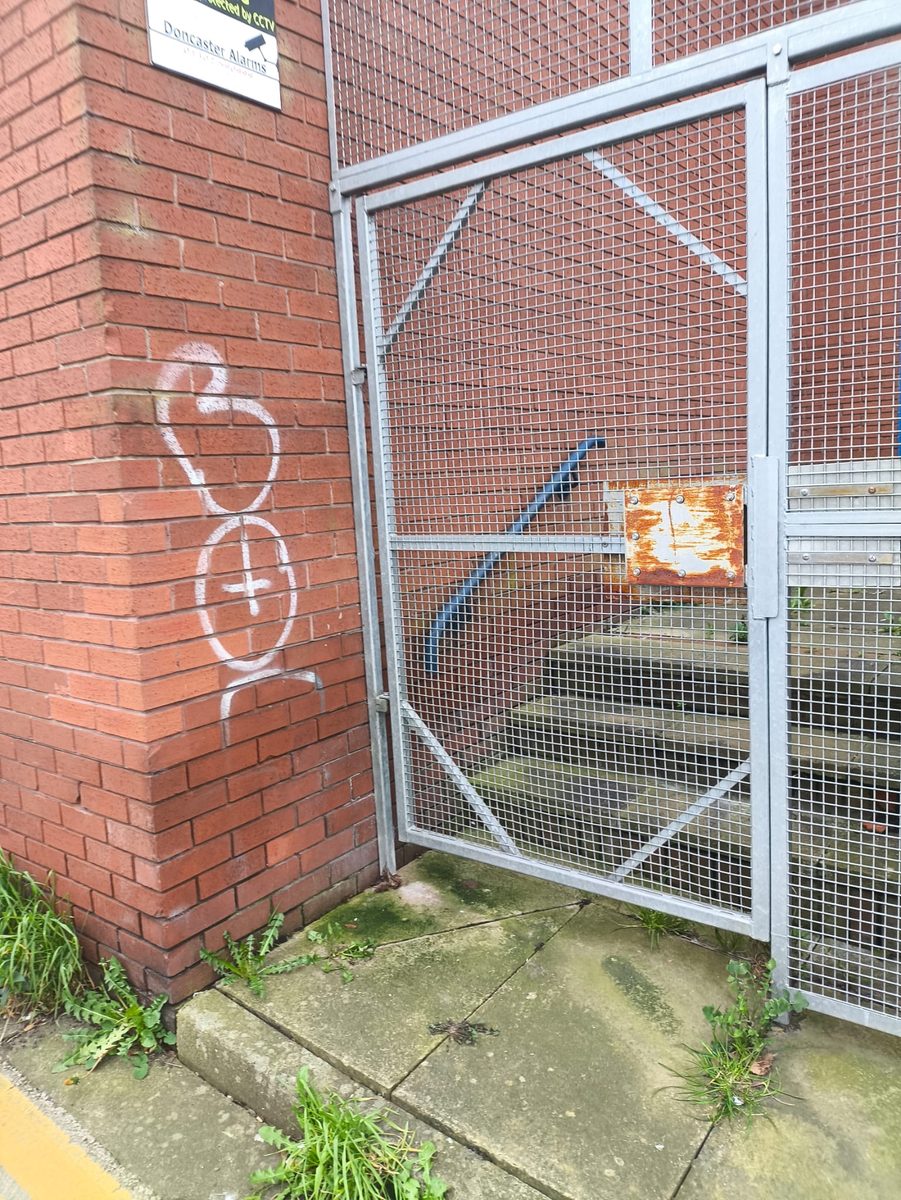 Graffiti spray paint on a brick pillar before cleaning