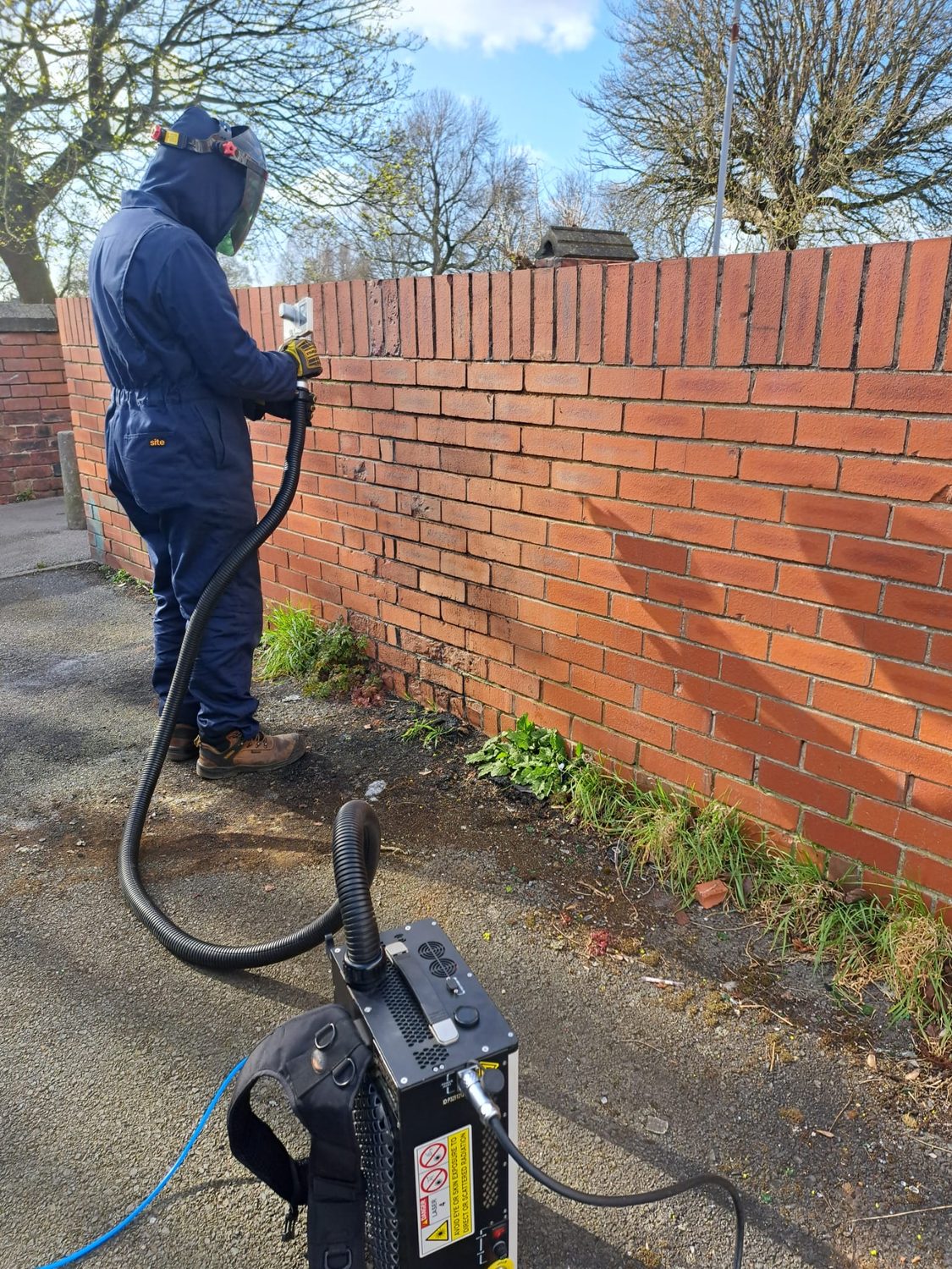 Laser Cleaning Experts technician using a laser to clean a brick wall